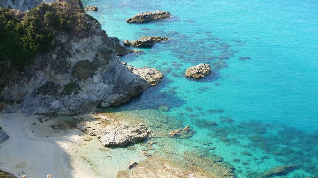 Scogliera e piccola spiaggia affacciate sul mare turchese di Capo Vaticano